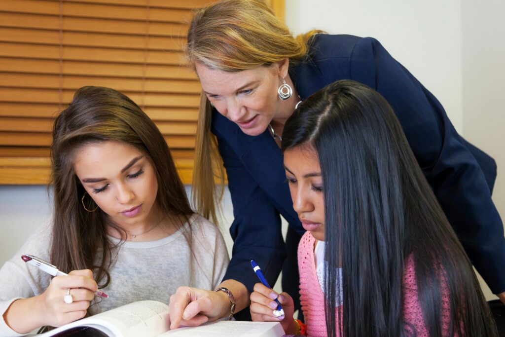 vrouwelijke docent helpt twee leerlingen met huiswerk